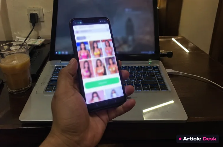 A man holding his phone over a laptop, looking at an escort site full of glamour photos