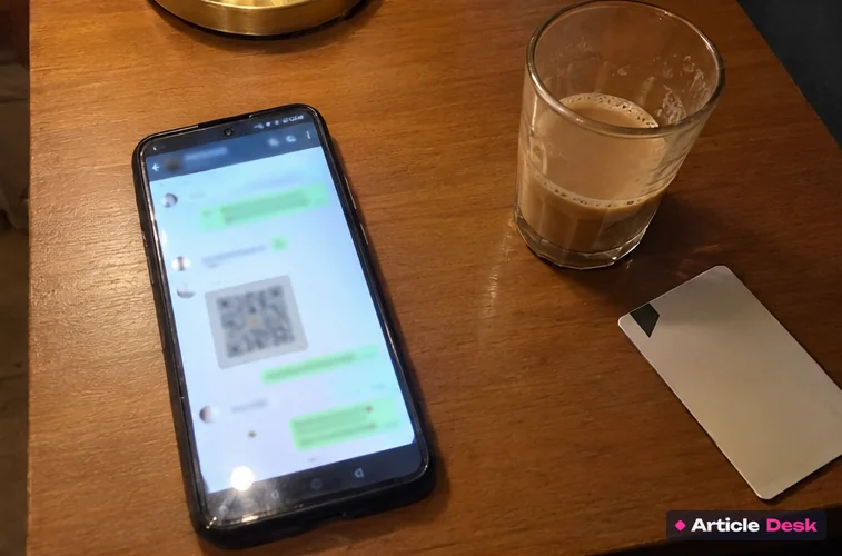 Phone on a table showing a WhatsApp chat where the account has sent a payment QR code